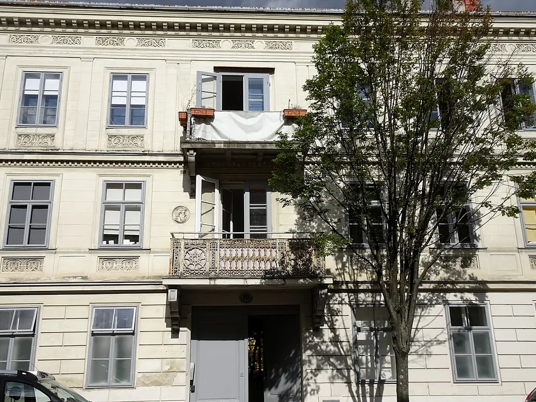 Gegliederte Wohnhausfassade mit mehreren Fenstern, Balkonen und Einheiten